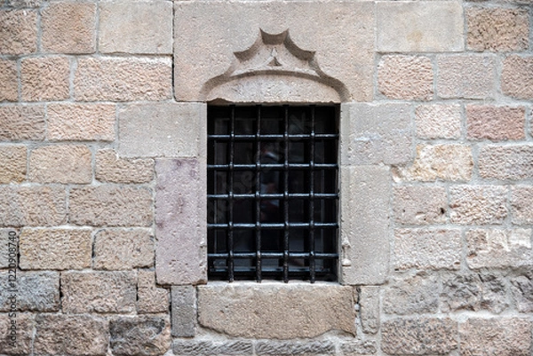 Fototapeta Rectangular window with black cast iron grille on old beige stone wall. From the series Windows of the World.