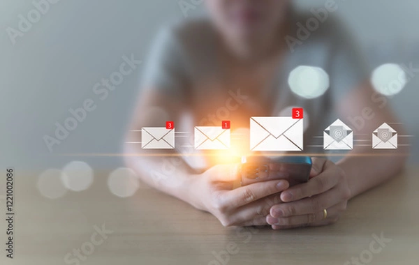 Fototapeta A woman sits and checks her email inbox to open it, whether it's for business or spam, using her mobile phone at home. convenient life, borderless communication with modern technology Background blur