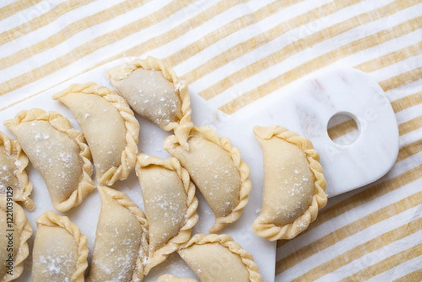 Fototapeta Fresh homemade dumplings prepared on a marble board, showcasing traditional handmade craftsmanship. Raw dough filled with savory ingredients, ready for cooking.