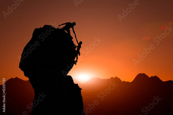 Fototapeta Team of climbers help to conquer the summit at sunset