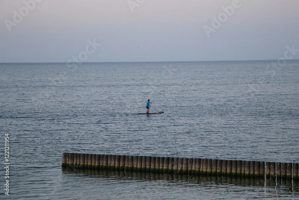 Obraz Man is doing standup paddling in sea at twilight