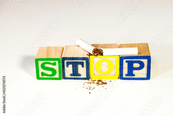 Obraz broken cigarette on wood blocks spelling stop with pieces of tobacco on white background