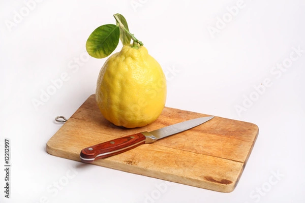 Fototapeta One lemon with knife on the board