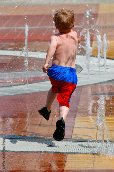 Fototapeta boy running and jumping through a fountain