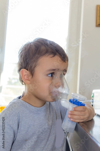 Fototapeta little boy using inhaler alone