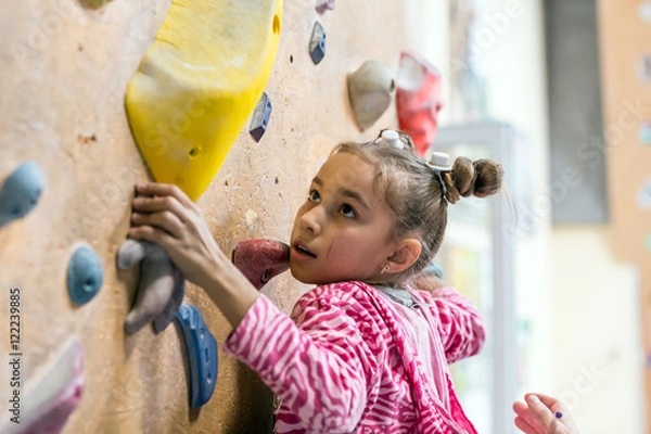 Fototapeta Junior Climber wiszący na uchwytach na ściance wspinaczkowej