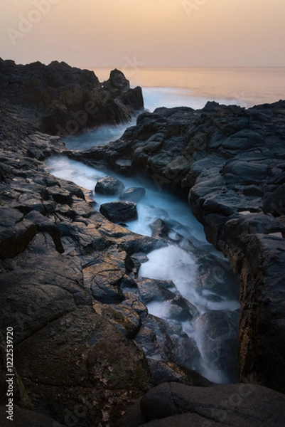 Fototapeta Scenic sunset view of rocky seashore with waves and misty water