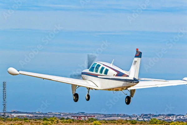 Obraz Light six-seat aircraft with wing tanks and retracting undercarriage taking off from airstrip in the Western Cape, South Africa