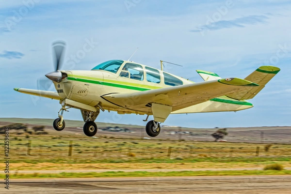 Obraz Light aircraft six-seat with green stripes and retracting undercarriage and unique V shaped tail taking off from an airstrip in the Western Cape, South Africa