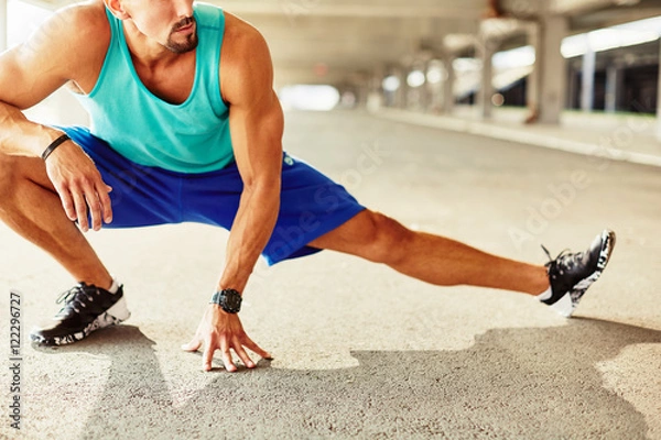Fototapeta Close up of male runner doing stretching exercise
