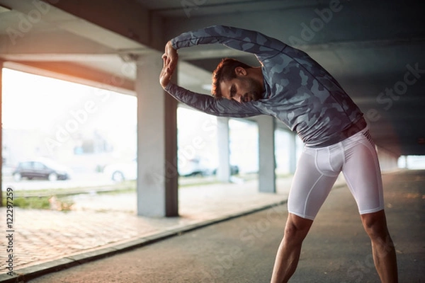 Obraz Young man stretching after running