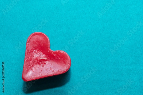 Obraz Red candle in the shape of a heart on a turquoise background with copy space. Love concept, Valentine's Day card, wedding. Add your text