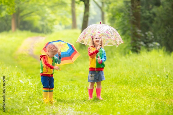 Fototapeta Kids playing in the rain with umbrella