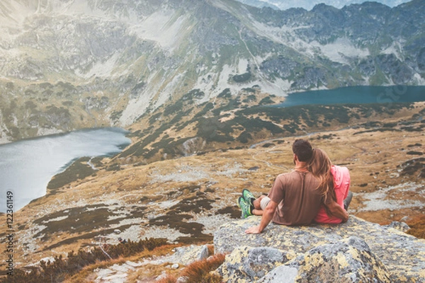 Obraz A young couple sitting on a rock and enjoying the view