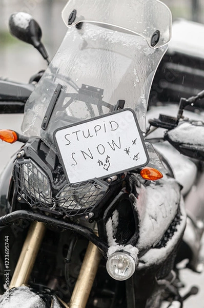 Fototapeta A large black touring motorcycle is covered in snow. The end of the motorcycle season, winter. The inscriptions "Stupid snow, No, WTF" symbolize stubbornness and the desire to continue traveling