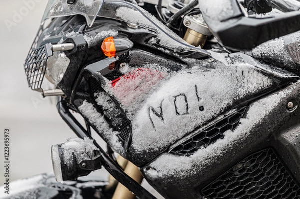 Fototapeta A large black touring motorcycle is covered in snow. The end of the motorcycle season, winter. The inscriptions "Stupid snow, No, WTF" symbolize stubbornness and the desire to continue traveling