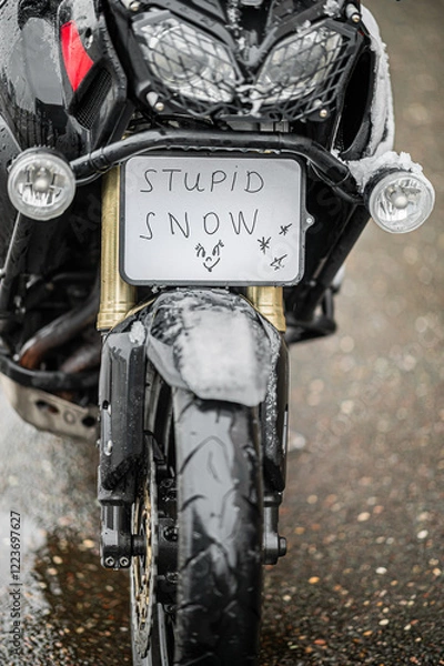 Fototapeta A large black touring motorcycle is covered in snow. The end of the motorcycle season, winter. The inscriptions "Stupid snow, No, WTF" symbolize stubbornness and the desire to continue traveling