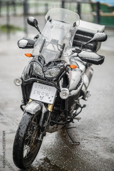 Fototapeta A large black touring motorcycle is covered in snow. The end of the motorcycle season, winter. The inscriptions "Stupid snow, No, WTF" symbolize stubbornness and the desire to continue traveling