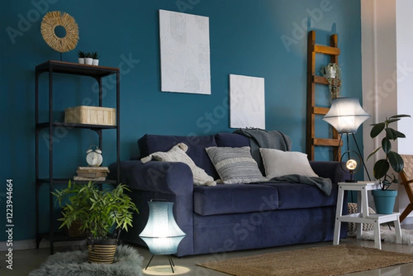 Fototapeta Interior of dark living room with blue sofa and glowing lamp
