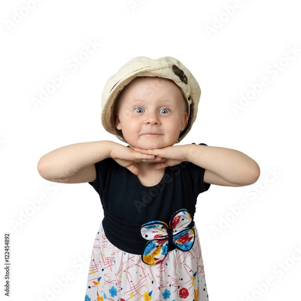 Obraz Cute round faced little girl with amazed facial expression and hands under chin posing in too big cap isolated on white background in square