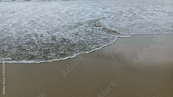 Fototapeta Close-up view of gentle waves lapping against the sandy shore, perfect for beach and relaxation themes