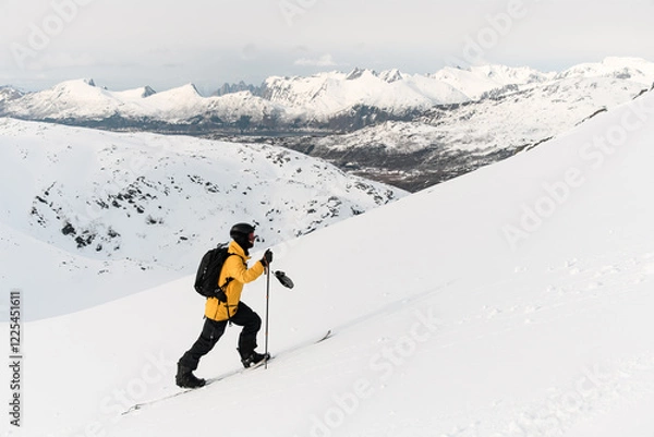 Fototapeta One-armed confident skier skis up the slope against a background of a beautiful mountains