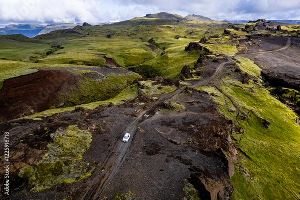Obraz Aerial drone view exploring a valley landscape with a lone white car 4x4 on a dirt road to Thakgil (Pakgil) campsite near Vik in Iceland