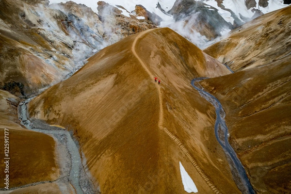 Obraz Scenic aerial drone view of a couple hikers in red jackets and foggy Kerlingarfjoll mountain path amidst desert and snowy terrain in Iceland