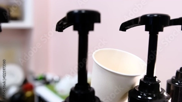Fototapeta Barista adds red cherry syrup to a white paper coffee cup using a dispenser at coffee shop creating delicious flavored drink with vibrant color perfect for coffee lovers seeking refreshing beverages