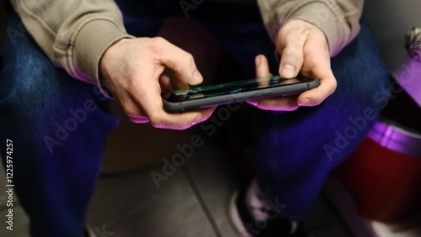 Fototapeta Young man playing mobile game with fast finger movements and colorful pulsating hand lights, dynamic gameplay, close up phone screen, digital entertainment, gaming action, energetic gaming session.