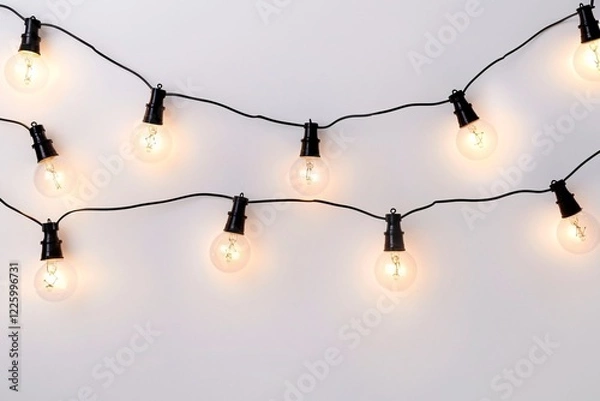 Fototapeta Row of vintage-style illuminated light bulbs hangs against a white backdrop
