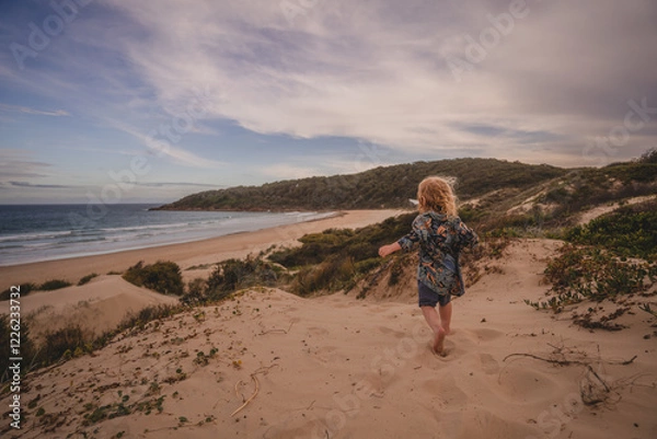 Obraz Young boy running down sand dune 