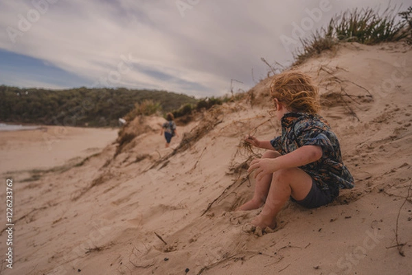 Obraz Toddler looking at person on beach sand dune
