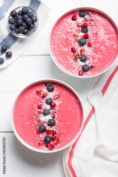Fototapeta Strawberry and beetroot smoothie bowls topped with blueberries, chia, pomegranate seeds and shredded coconut. Top view