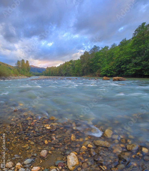 Fototapeta Bubbling streams of the mountain river at sunset.