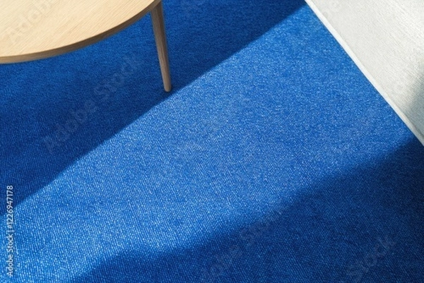 Obraz close-up of modern living room setup with bold blue rug beneath minimalist coffee table under soft light