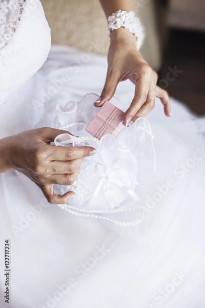 Fototapeta Bride pulls out a purse box with wedding rings or a gift from th