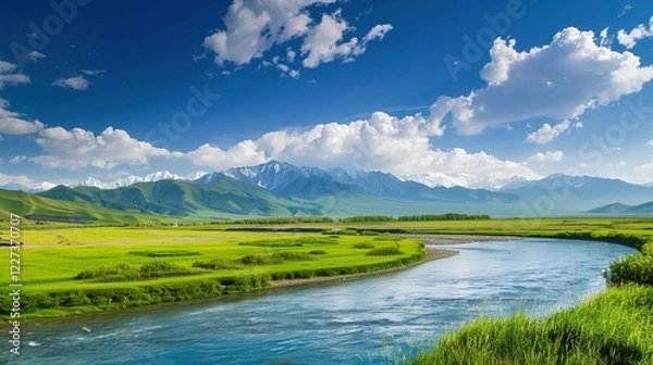 Obraz A beautiful green field with a majestic mountain, a clear river and a vast sky in the background. The idyllic and serene natural scenery creates a peaceful and charming atmosphere.