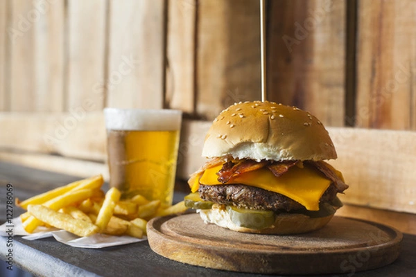 Fototapeta Tasty hamburger with fries and glass of beer on counter.