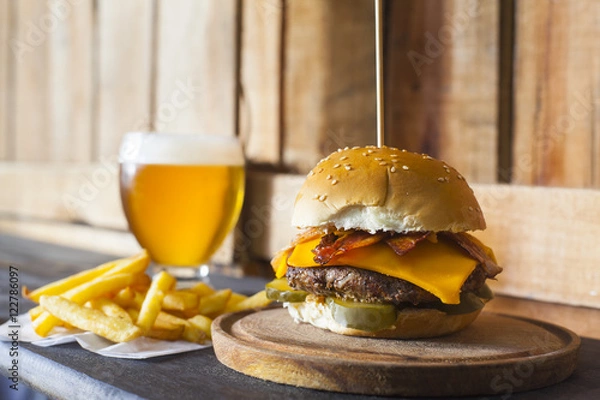 Fototapeta Tasty hamburger with fries and glass of beer on counter.