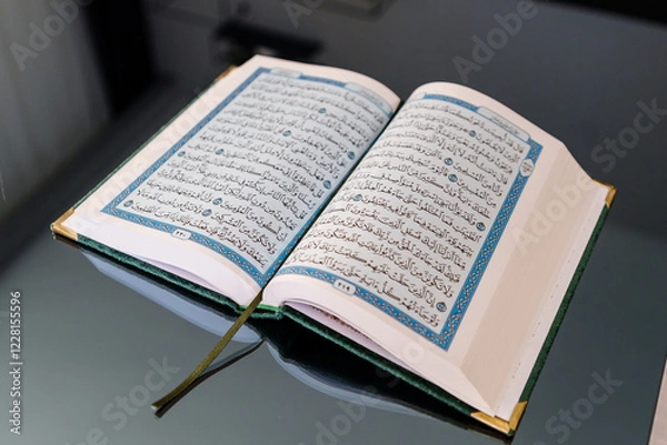 Fototapeta Open Quran Book Featuring Arabic Script With Blue Decorative Details. Ramadan