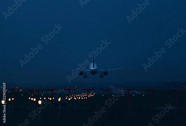 Fototapeta An airplane flies over the runway for landing