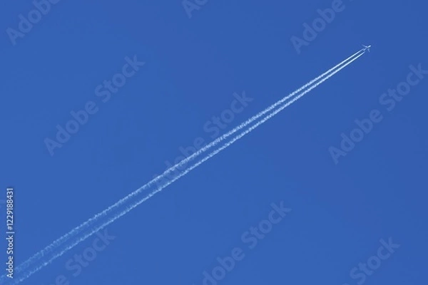 Fototapeta Plane with contrails in the blue sky, Germany, Europe