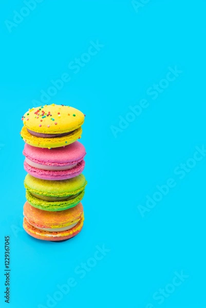 Obraz Few brightly colored stacked macarons on blue background. Mixed of colorful macaroni or pasta cake. Tasty and colorful french macarons. Culinary, cooking concept, styling food. Add your text. Vertical