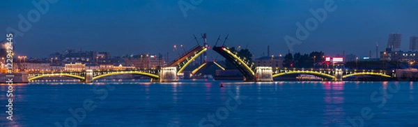 Fototapeta Night panoramic view of illuminated Neva River and open Birzhevoy Bridge and Tuchkov Bridge, Saint Petersburg, Russia.
