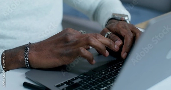 Fototapeta A man typing on a laptop, sitting at a table indoors, close-up of his hands, an unrecognizable person