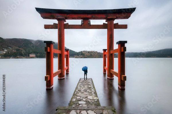Obraz Person standing under red torii gate at Lake Ashi, Hakone, Kanagawa Prefecture, Japan