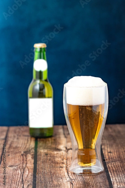Obraz Golden Beer in a Glass with Foam and Green Bottle on Rustic Background – Beer Glass and Bottle Mockup in Rustic Style