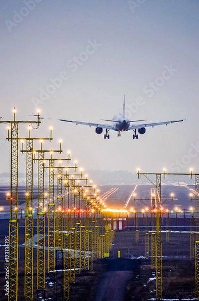 Fototapeta Airplane landing at the airport runway in evening