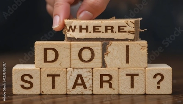 Fototapeta Wooden blocks spelling out the question 'Where do I start?', a hand placing the 'Where' block.